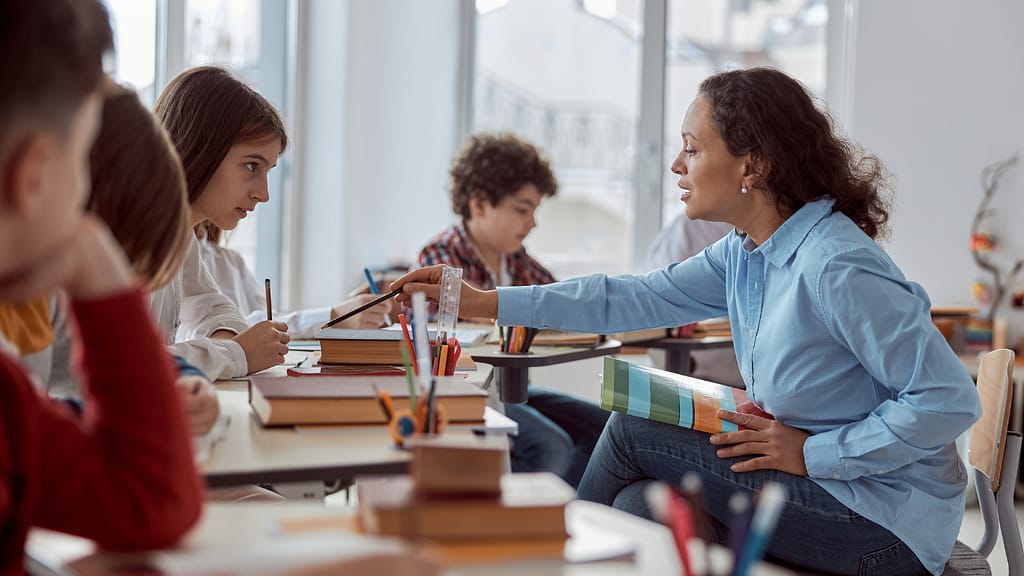 A teacher explaining a topic to her student, emphasizing the importance of teacher pay.