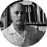 Todd Votteler wearing a guayabera and standing in front of a bookcase