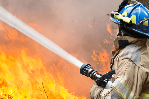 A firefighter putting out a wildfire, emphasizing the importance of enhanced wildfire response in Texas.