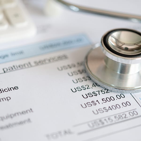 A stethoscope and calculator on top of a medical bill, emphasizing the importance of price transparency in health care.